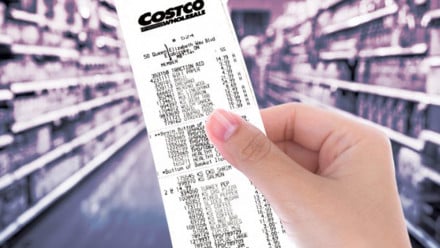A woman holds a huge receipt from Costco