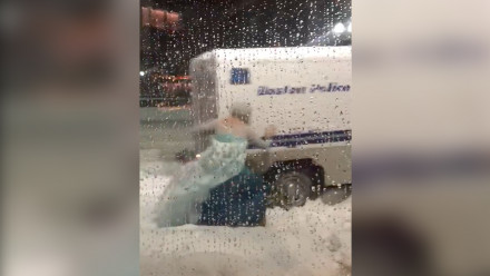 Man dressed up as Queen Elsa pushes a truck out of a snowbank