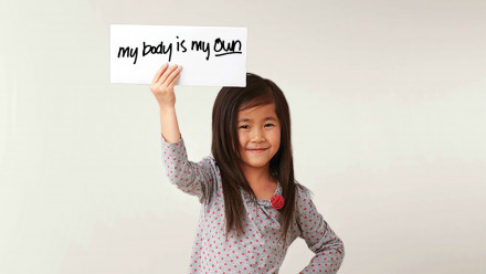 A little girl holding a sign up that says My body is my own