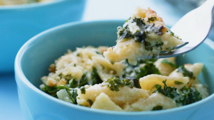 A bowl of macaroni and cheese with kale in it
