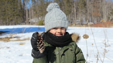Little girl holding a pine cone.