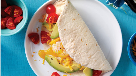 Tortilla wrap filled with eggs, cheese, avocado and tomato