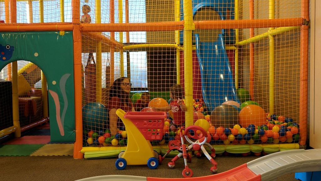 Photo of a mom and kids playing in a ball pit at the Kinderland Indoor Play & Cafe