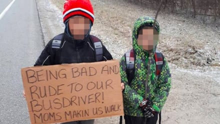 Photo of two kids holding a sign that says they were being rude to the bus driver and had to walk to school.