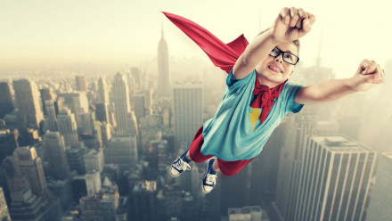 A boy dressed as a superhero flying over New York City.