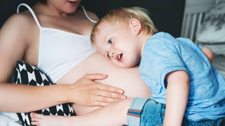 Little boy hugging moms belly during her second pregnancy