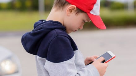 kid wearing a red baseball cap on a smartphone