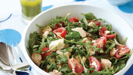 Bowl of arugula with chopped tomatoes and chicken
