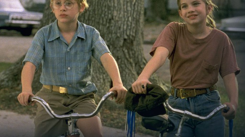 Still from My Girl with Vada and Thomas J on their bikes in front of Mr Bixler's house