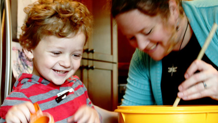 Photo of a mom and toddler son cooking together in the kitchen