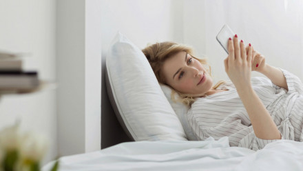 A woman lying in bed, looking at her phone