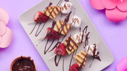 Skewers of strawberry shortcake drizzled with chocolate on a plate