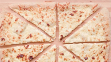 a white cheesy pizza cut into triangular slices