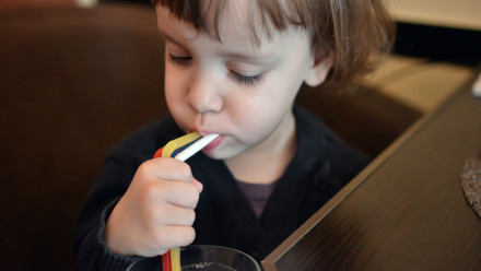A baby drinking from 3 straws.