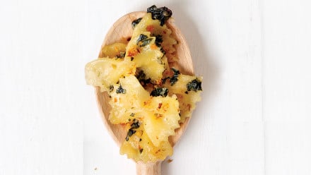 Bowtie pasta on a wooden spoon with kale and breadcrumbs
