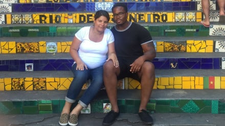Photo of a man and his pregnant wife sitting on stairs.