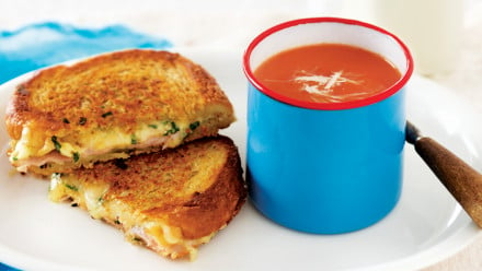 Cup of tomato soup with grilled cheese sandwich with swiss and ham