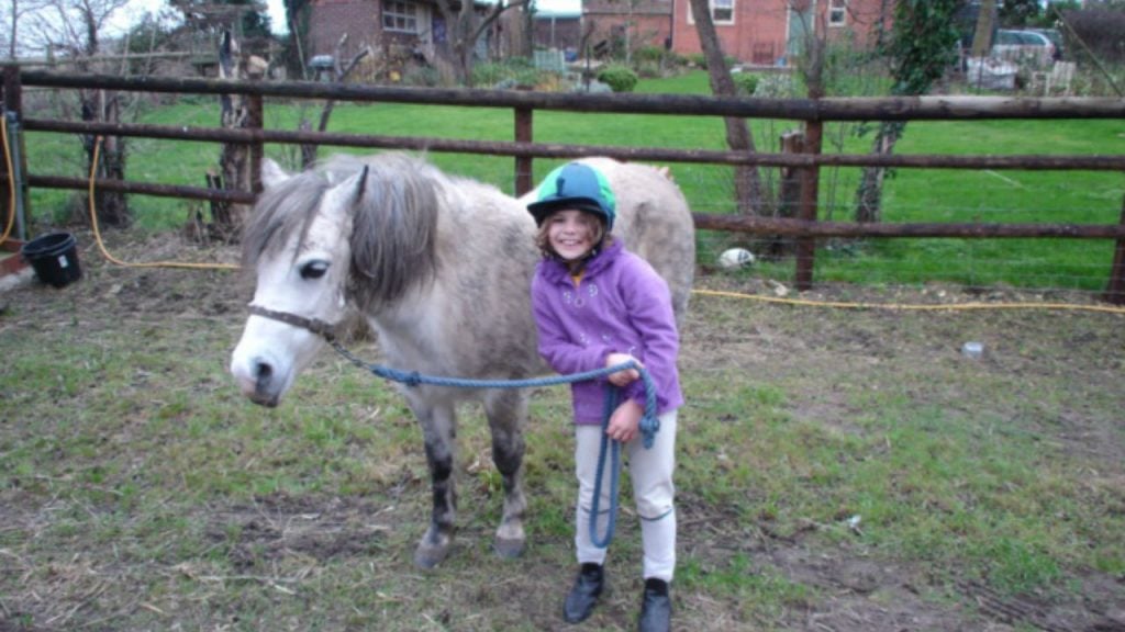 A young girl standing with a horse. 