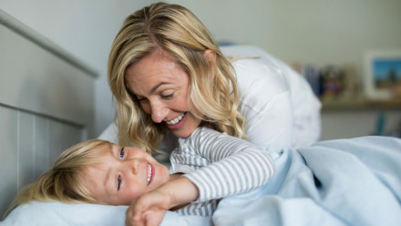 A mother and her son laughing in the bed.