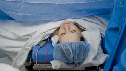 Woman under a surgical curtain about to have a c-section