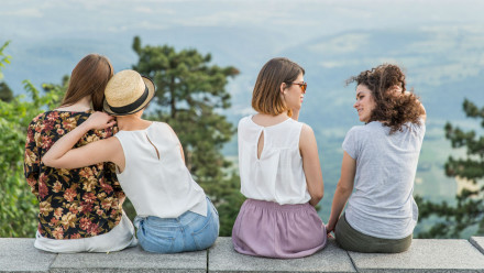 Four young women sitting together with their backs facing the camera