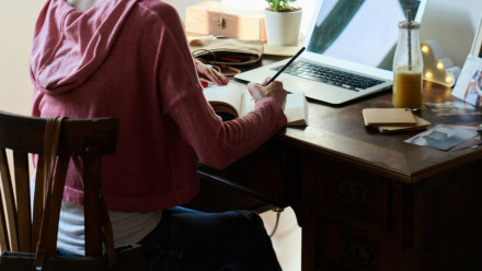 A woman at a desk, writing in a notebook