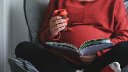 A pregnant woman sitting and reading a pregnancy book