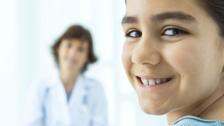 A young girl smiling as the female doctor looks at a clinic.