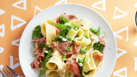 Plate of broad pasta noodles with fresh peas and prosciutto
