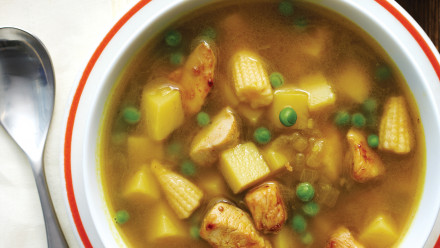 Bowl of soup with chicken, potatoes, baby corn and peas