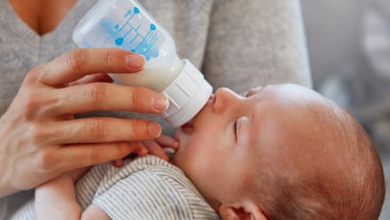 Closeup shot of a mother feeding her newborn baby from a bottle