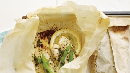 White fish in parchment paper package with lemons and green beans