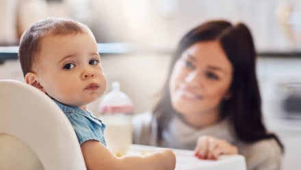 baby giving side-eye in high chair while mom looks on