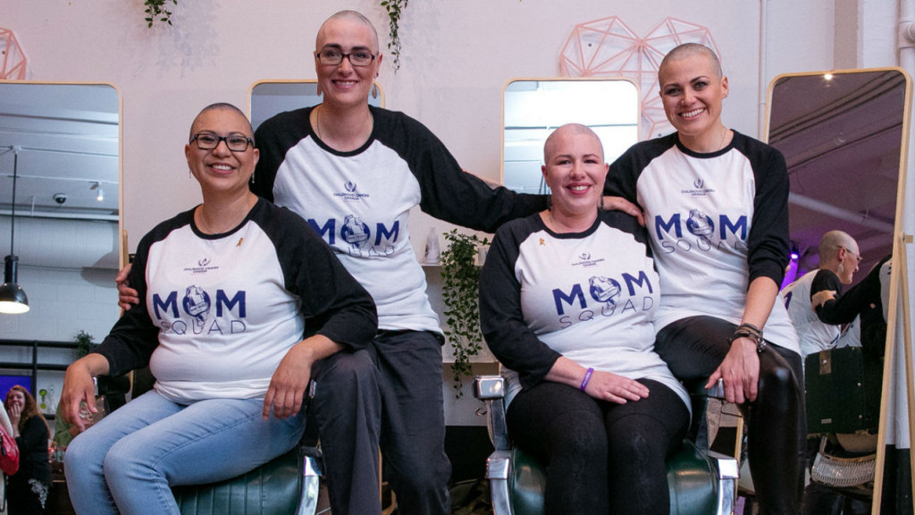 A group of women getting photographed after getting heads shaved 