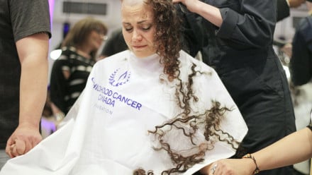 A woman getting emotional while getting her head shaved.
