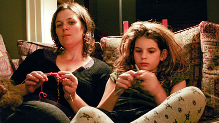 Mother and daughter sitting on a couch, knitting