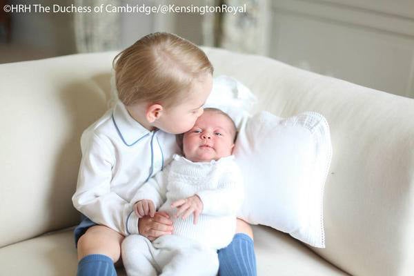 Prince George kissing a baby Princess Charlotte on the head