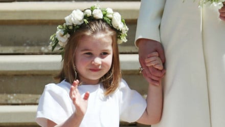 Princess Charlotte waving in a white dress at the royal wedding