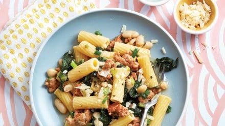 Plate of rigatoni with crumbled sausage, kale, white beans and grated cheese