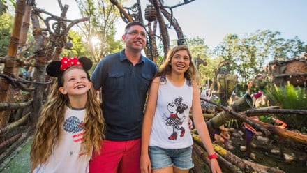 Dad and two daughters walking through a Disney park