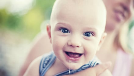 A baby smiling and drooling because of getting first molars