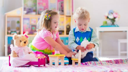 a boy and a girl playing with doll house.