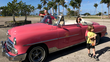 Family sitting in a pink convertible