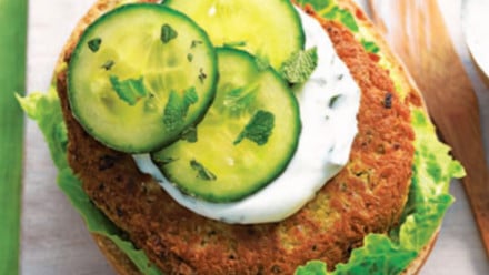 Chickpea falafel patty on a bun with yogurt and sliced cucumber