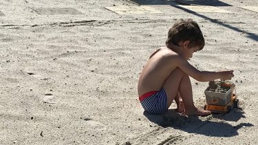 Little boy playing with a truck in the sand