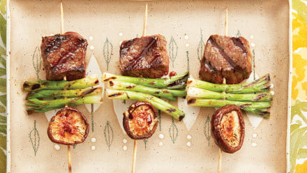 sticks with cube of steak, green onions and a mushroom cap