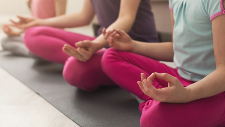 Closeup of mother and daughters hands doing meditation on yoga mats at home