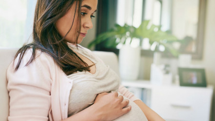 A pregnant woman sitting using her laptop