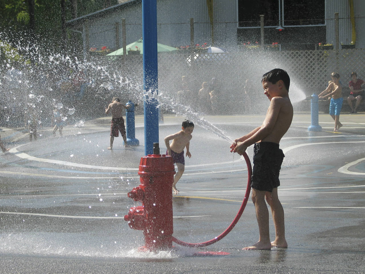 A little boy playing with a hose at Granville Island water park