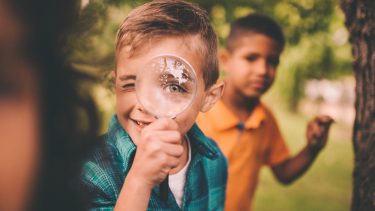 kid with magnifying glass and friend looking behind him